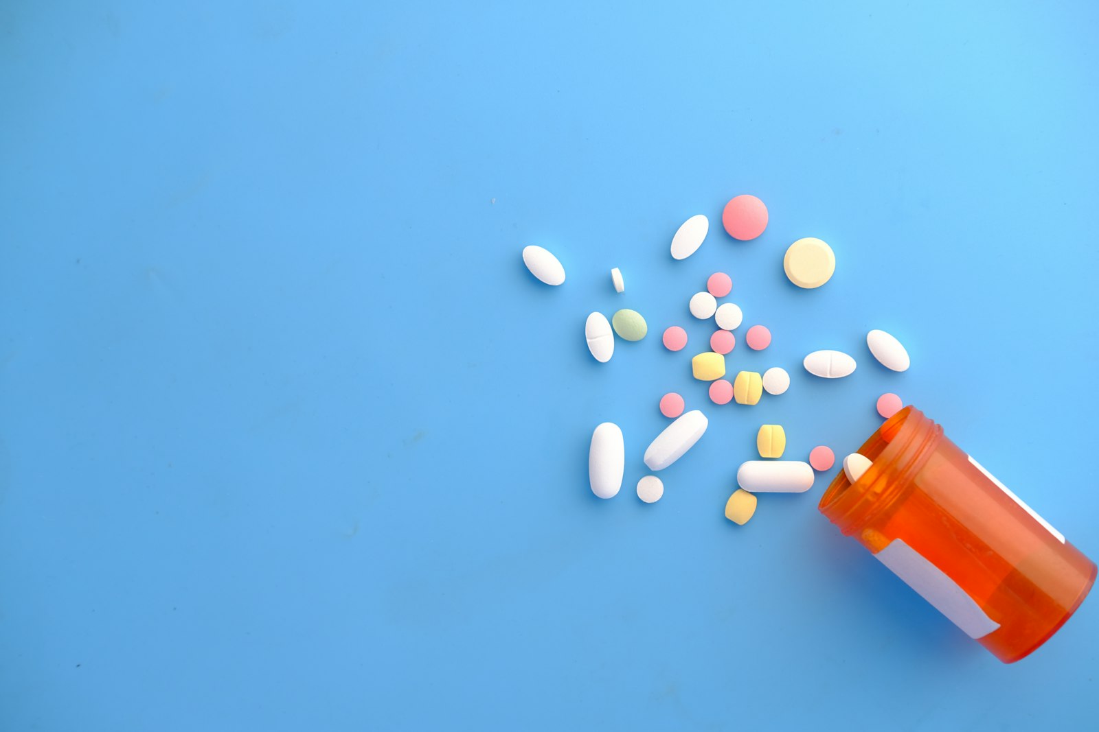 Prescription bottle with medication on a light blue background