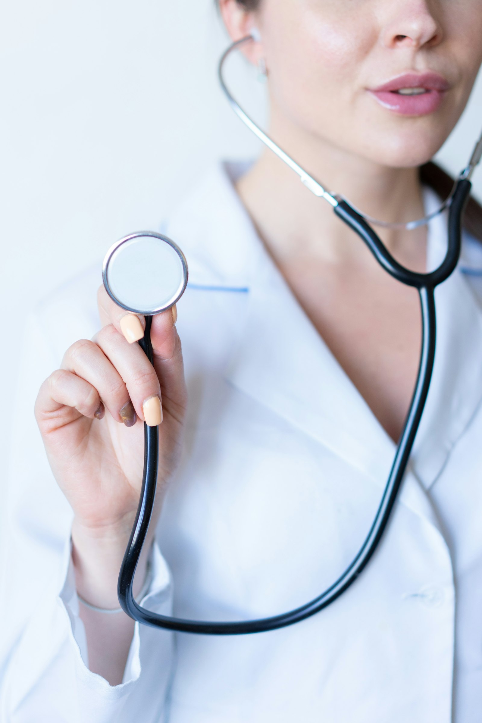 Healthcare professional in a white coat holding a stethoscope (stock photo)